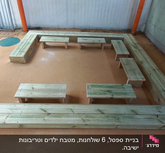 ספסלי עץ מסודרים בצורת ריבוע בחצר מגודרת